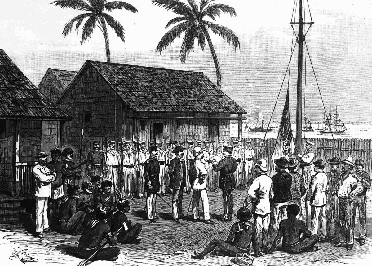 Indigene und weiße Männer sitzen und stehen rund um einen Masten, auf dem eine Fahne gehisst wird. Vier Männer, einer davon mit weißem Anzug, stehen in der Mitte. Im Hintergrund das Meer mit Schiffen, links drei Häuser und zwei Palmen.  © Wikimedia 