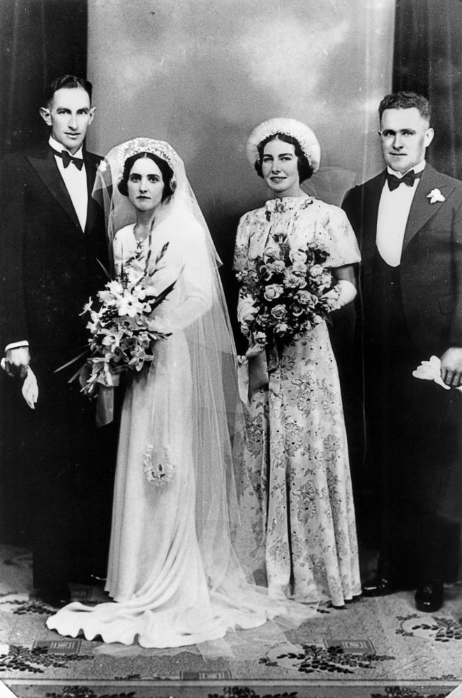 Zwei frisch vermählte Ehepaare in Hochzeitskleidung, die Frauen mit weißen Kleidern, Blumensträußen und Schleier, die Männer in Smoking mit Fliege. © Wikimedia