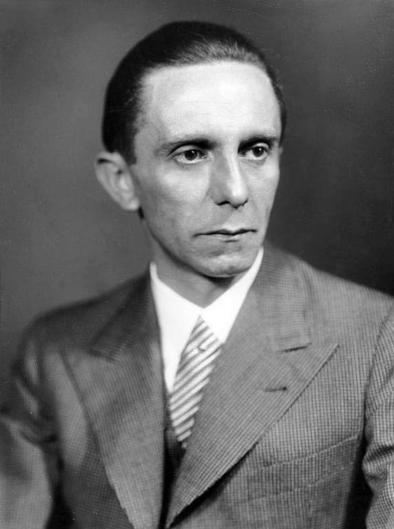 Das Portraitfoto zeigt Josef Goebbels in Sakko und Krawatte. Er hat einen ernsten Gesichtsausdruck und trägt die Haare zurückgekämmt.  © Wikimedia, Bundesarchiv, Bild 146-1968-101-20A, Heinrich Hoffmann, Joseph Goebbels, CC-BY-SA 3.0.