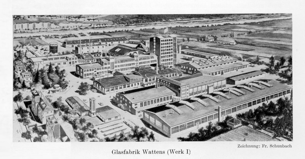 Schwarzweißfoto der Fabrik in Wattens mit etlichen Fabrikhallen und weiteren Gebäuden. Im Hintergrund befinden sich Felder und ein Fluss.  © Wikimedia, Werk I Swarovski in Wattens. 