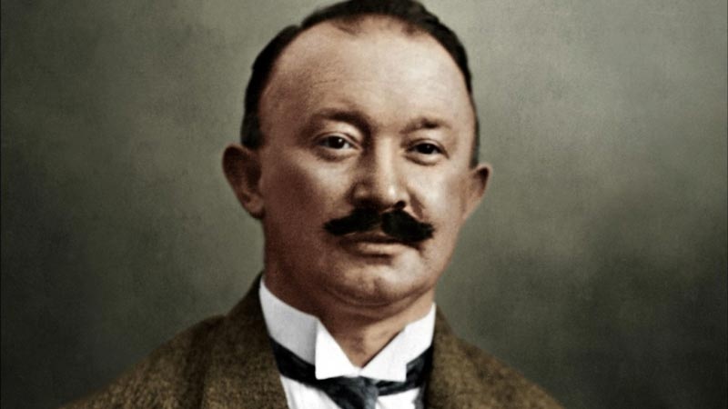 Das Portraitfoto zeigt Hugo Ferdinand Boss. Er trägt eine braune Jacke, ein weißes Hemd und eine schwarze Krawatte. Sein Gesicht ist rund und er hat eine Halbglatze. Er trägt einen Schnurrbart.  © Wikimedia, Hugo Ferdinand Boss, 1933. 