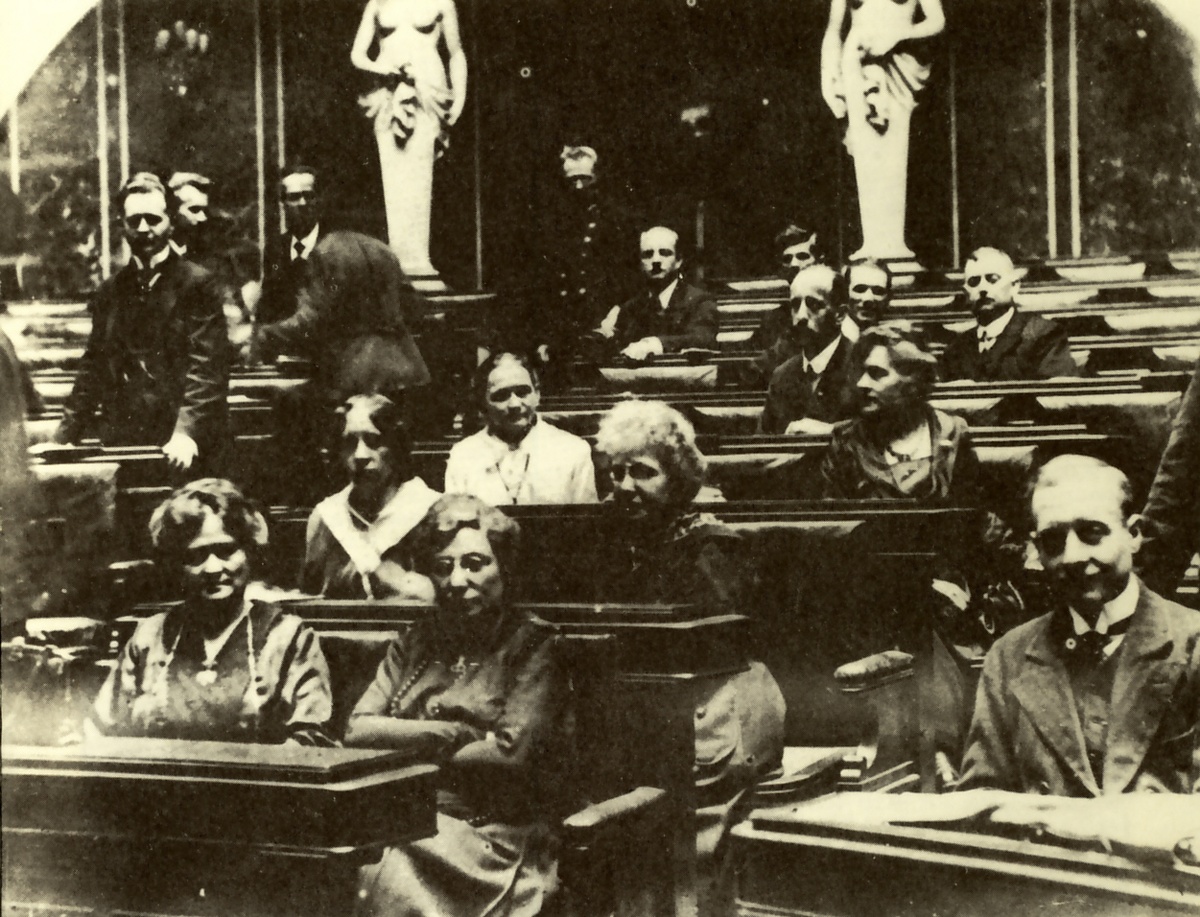 Bei der Nationalversammlung vom 4. März 1919 sitzen in den Sitzreihen zwischen männlichen Abgeordneten die ersten weiblichen Abgeordneten. Darunter ist auch Amalie Seidl. Sie sitzt in der dritten Reihe.  © Wikipedia