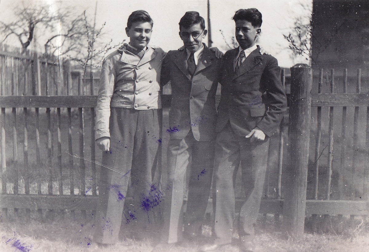 Drei Jugendliche in Anzügen stehen vor einem Gartenzaun. Im Hintergrund eine Wiese, Baumwipfel und ein Teil einer Hausmauer.  © Wikimedia