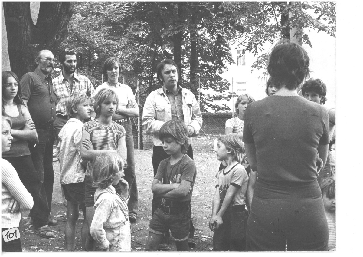 Mehrere Kinder und Erwachsene unterschiedlichen Alters stehen auf einer Wiese vor B&auml;umen und schauen skeptisch bis interessiert. &copy; Gartenhofverein Planquadrat, Filmteam im Gespr&auml;ch mit Anrainer:innen