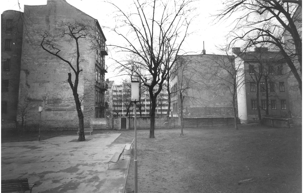 Die Schwarzwei&szlig;fotografie zeigt einen kargen Hof mit einzelnen B&auml;umen und mehrst&ouml;ckigen H&auml;usern mit Fassaden ohne Fenster.  &copy; Gartenhofverein Planquadrat, Innenhof