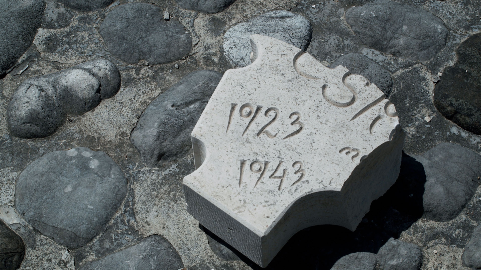 Ein abgebrochener Teil eines Grabsteins liegt auf Steinboden. Auf dem Stein sind die Zahlen 1923 und 1943 eingraviert.  © Hollaus, Messner, Lammerhuber, 2022