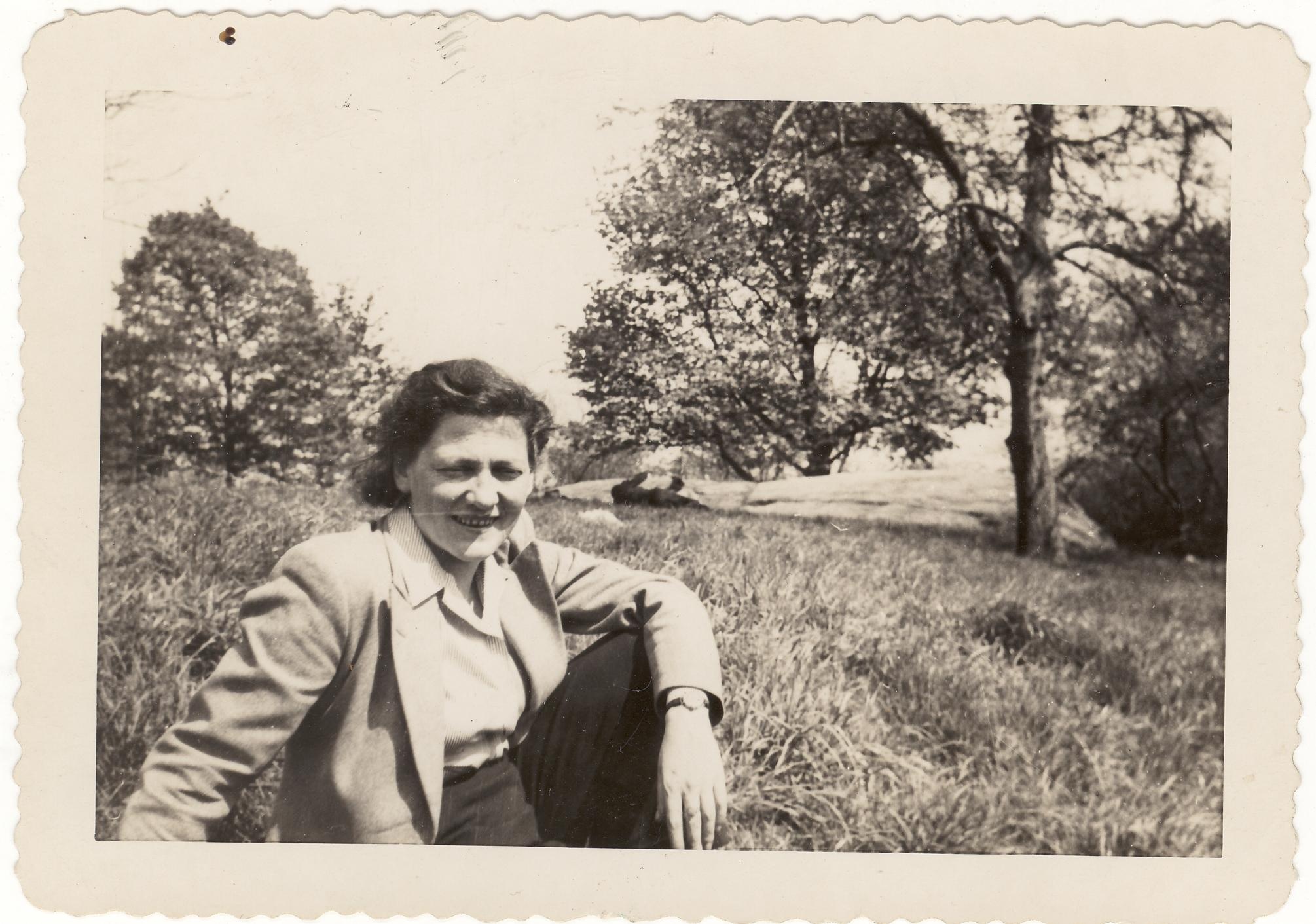 Marie Jahoda sitzt in einer hellen Jacke mit Kragen in einem Park. Sie trägt die Haare zurückgesteckt. Im Hintergrund befinden sich hohes Gras und einige Bäume.  © Archiv für die Geschichte der Soziologie in Österreich 