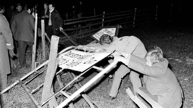 Zwei Personen reißen eine zweisprachige Ortstafel in Kärnten nieder. © GERT EGGENBERGER / APA / picturedesk.com