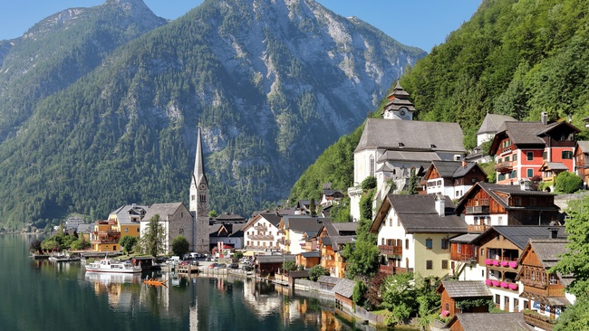 Blick auf das Zentrum von Hallstatt. Am Ufer des Hallst&auml;tter Sees stehen H&auml;user mit Giebeld&auml;chern. Links im Bild steht eine Kirche mit einem spitz aufragenden Kirchturm. Im Hintergrund befinden sich Berge, die teilweise bewaldet sind.  &copy; Wikimedia, C.Stadler/Bwag, Hallstatt (CC-BY-SA-4.0). 