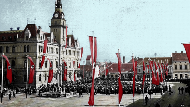 Ein großer Platz vor dem großen mehrstöckigen Rathaus. Mehrere hohe Hakenkreuzfahnenreihen sind zu sehen. Im Zentrum des Platzes stehen mehrere Hundert Personen. Dahinter sind niedrigere Häuser zu sehen.   © Bildarchiv des Vereins zur Förderung der Erneuerung von Laa an der Thaya