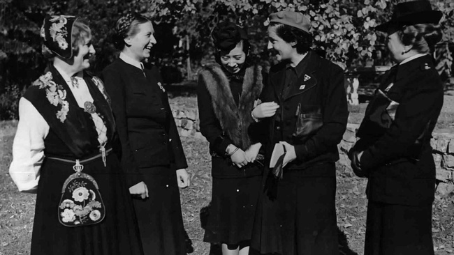 nf Frauen in dunklen Mänteln stehen in einem Park oder Garten beieinander, lachen und reden. Links steht die norwegische Frauenführerin Bjoner in Tracht mit Blumenmustern, rechts davon die Reichsfrauenführerin Scholtz-Klink mit einer Flechtfrisur, in der Mitte Frau Oshima, Gattin des japanischen Botschafters, mit Pelz und rechts die spanische Frauenführerin Primo de Rivera und die Italienerin Olga Medici, beide mit Hut.  © ÖNB Bildarchiv, Treffen faschistischer Frauen in Berlin, 1941. 