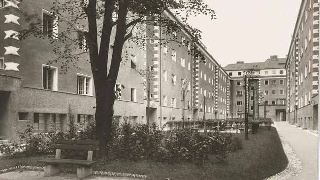 Ein Innenhof wird von fünfstöckigen Hausblöcken gesäumt. Im Hof befindet sich eine kleine Wiese mit einem Baum.  © Wien Museum, Wohnhäuser in der Penzinger Straße, Martin Gerlach, 1926. 