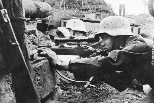 Zwei junge Soldaten in Uniform, mit Helm und Maschinengewehr in einem Schützengraben.  © Wikimedia