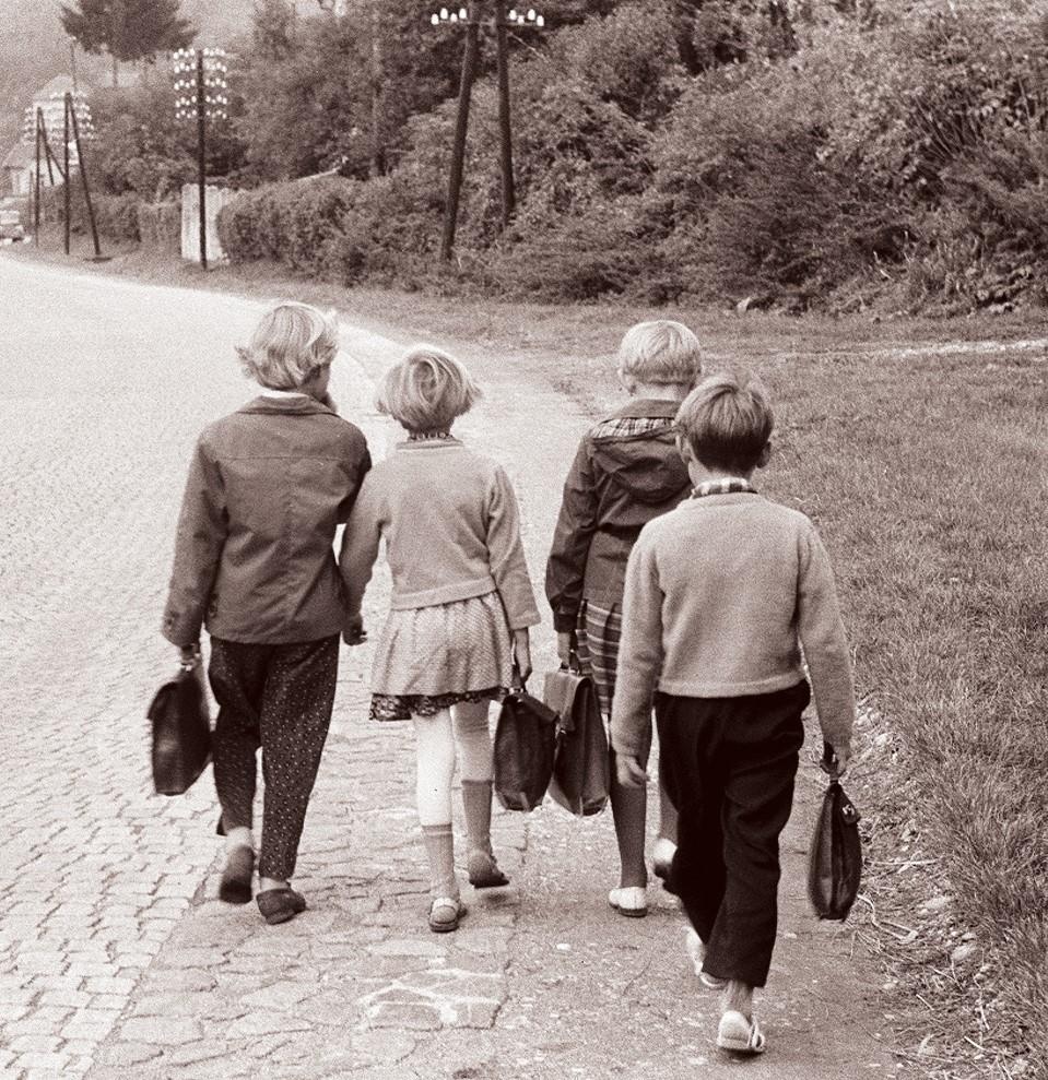 Vier Kinder gehen am Straßenrand entlang, jedes hat eine Tasche in der Hand.  © Wikimedia. 